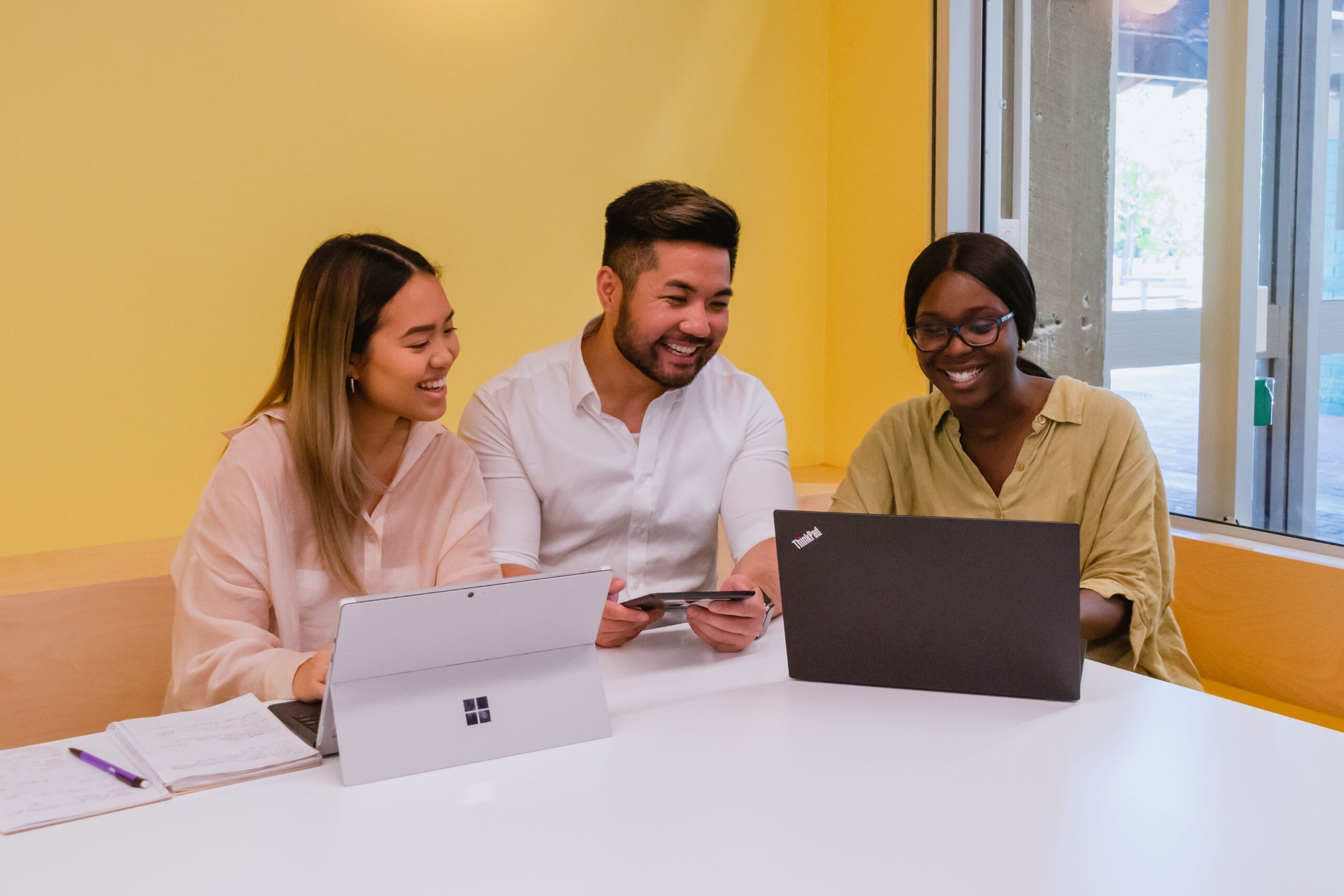 3 students sitting at a desk with laptops
