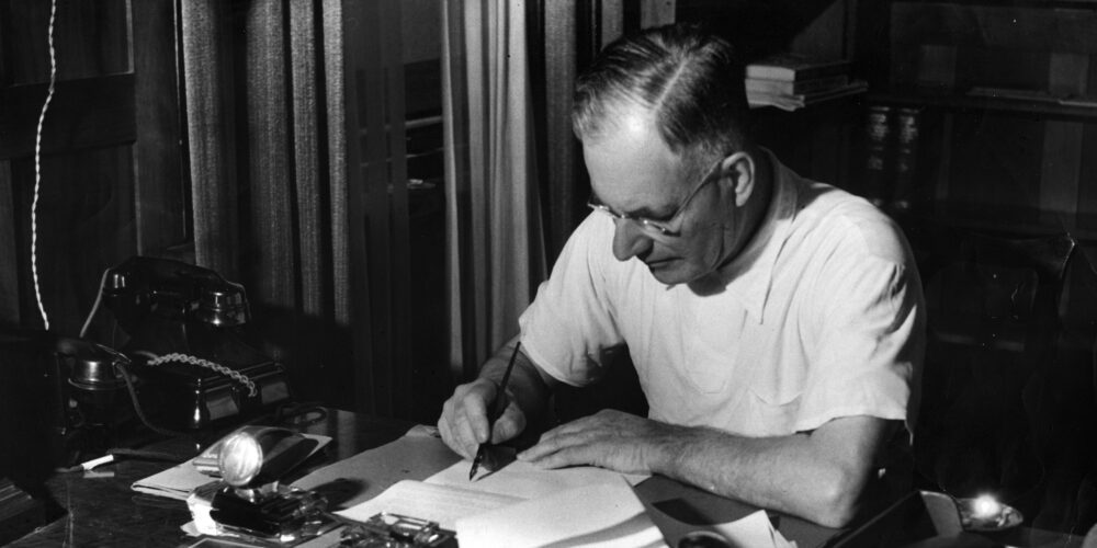 John Curtin sits at a desk writing a document