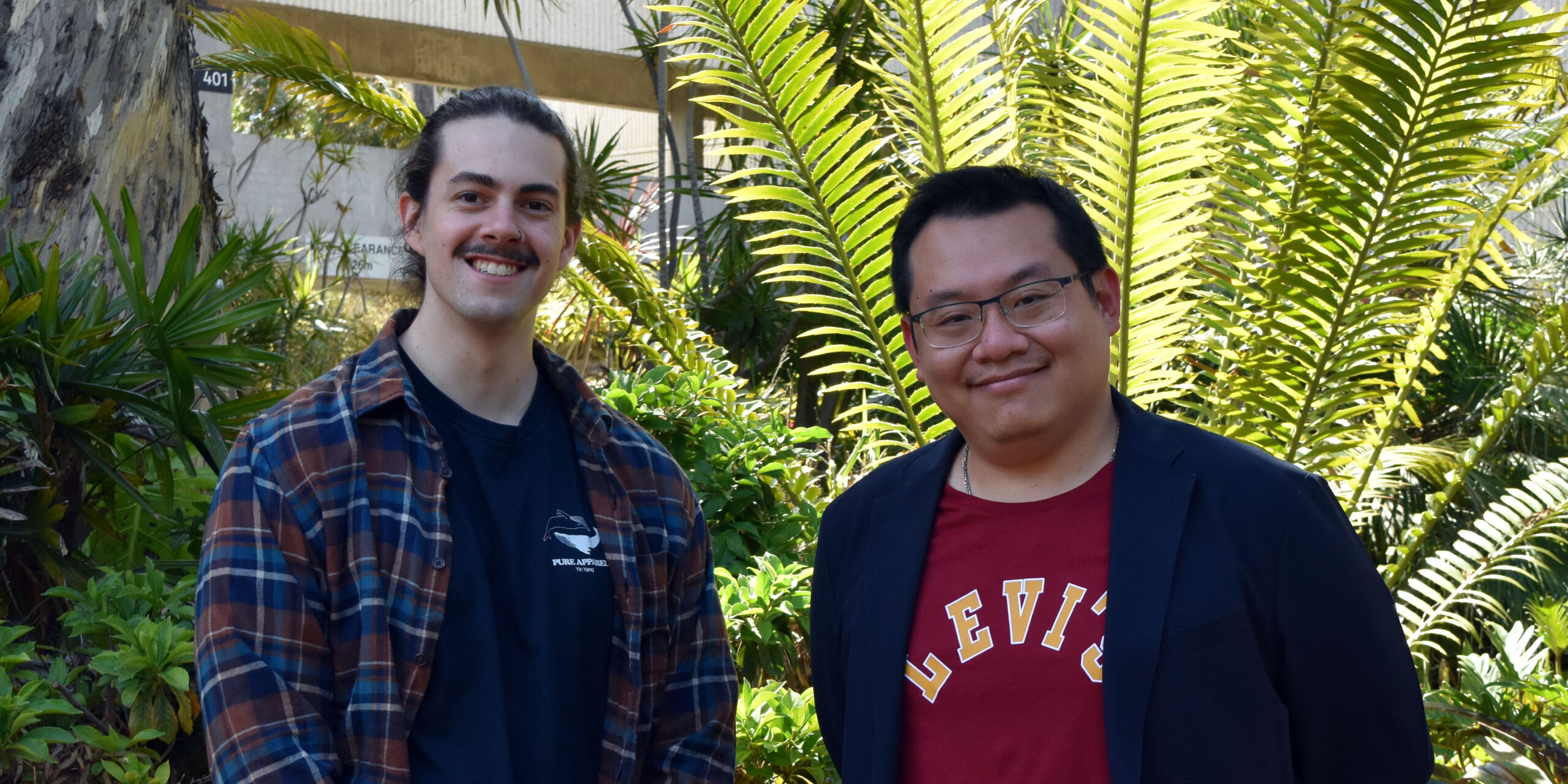 Alexander Hamilton and his supervisor Dr Hendra Gunosewoyo smile at the camera, standing on Curtin campus in front of foliage