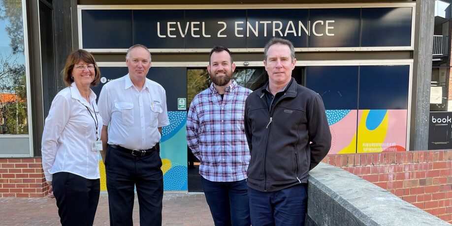 Cindy Carbutt, Chris Wright, James Robinson and Colin Sinclair from the Library Spaces Group stand in front of the level 2 entrance of the TL Robertson Library, smiling at the camera.