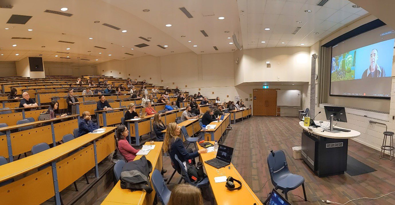 Students sitting in a lecture theatre looking at a presentation on the screen