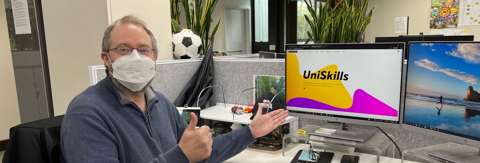 Staff member looking at the camera with thumbs up and UniSkills webpage open