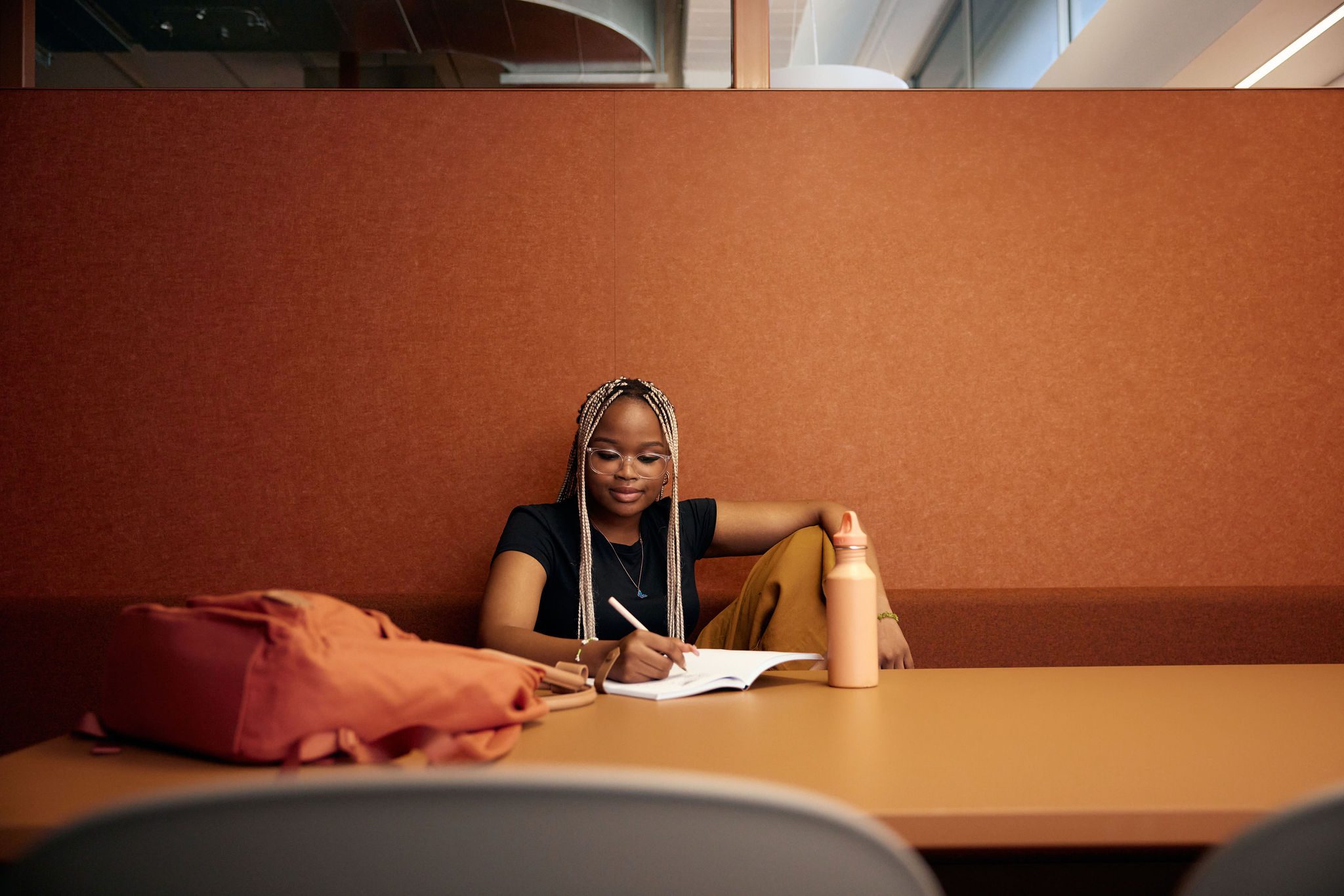 Student sitting in a study pod writing