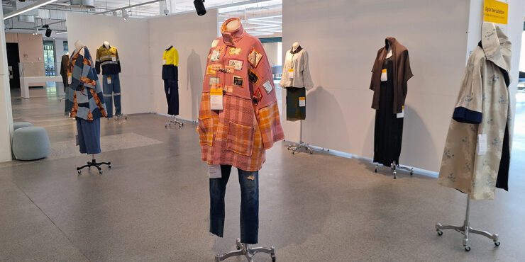 Photo of the digital twin exhibition, with a sign and manniquins with clothes on them.