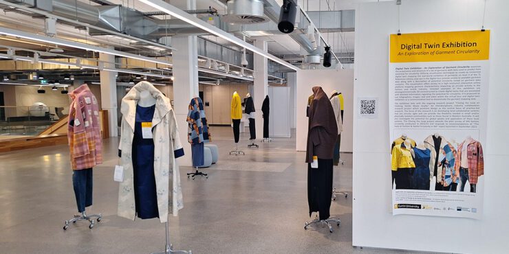 Photo of the digital twin exhibition, with a sign and manniquins with clothes on them.